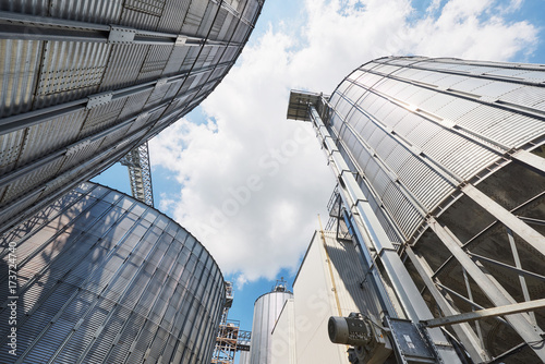 Agricultural Silos. Building Exterior. Storage and drying of grains, wheat, corn, soy, sunflower against the blue sky with white clouds