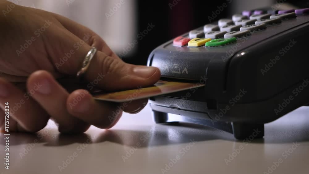 A girl makes a purchase with a bank or credit card using an electronic chip in the card. Insert a card into the terminal of a non-cash payment