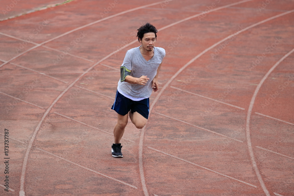 Obraz premium Lifestyle of young healthy Asian runner man running on racetrack in stadium