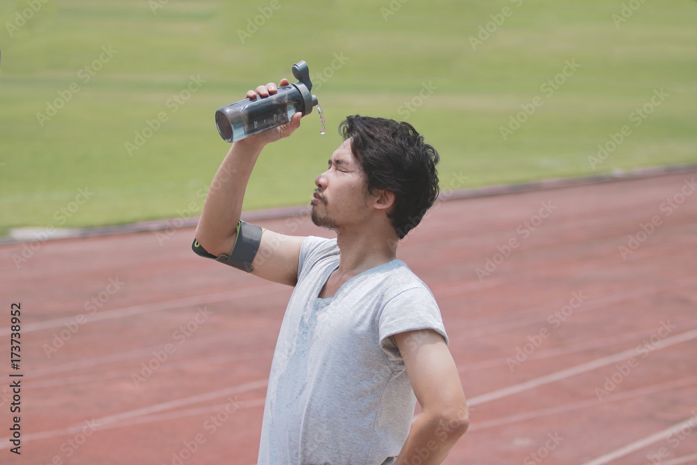 Φωτογραφία Healthy young Asian fitness man splashing water on his face after run in track of stadium