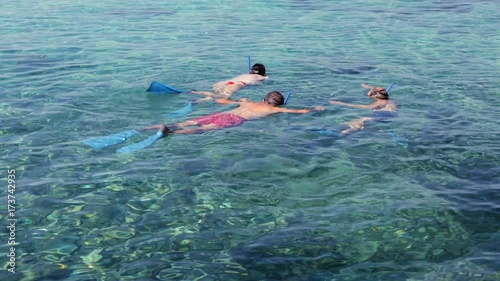 Snorkelling. A group of people in masks with tubes floats in the sea.