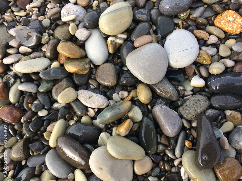 Naklejka premium background, beach, wallpaper, stone, pebble, texture, natural, colorful, abstract, sea, pattern, nature, smooth, photo, color, closeup, surface, shape, pebbles, rock, material, gravel, black, decorati