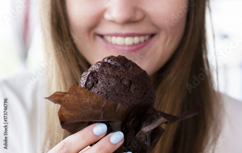 Girl eating a muffin in coffeeshop. Girl eating a cupcake.To enjoy a chocolate muffin.
