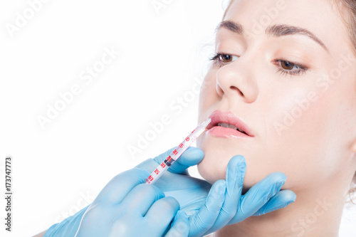 Young woman having lip-plumping injections.