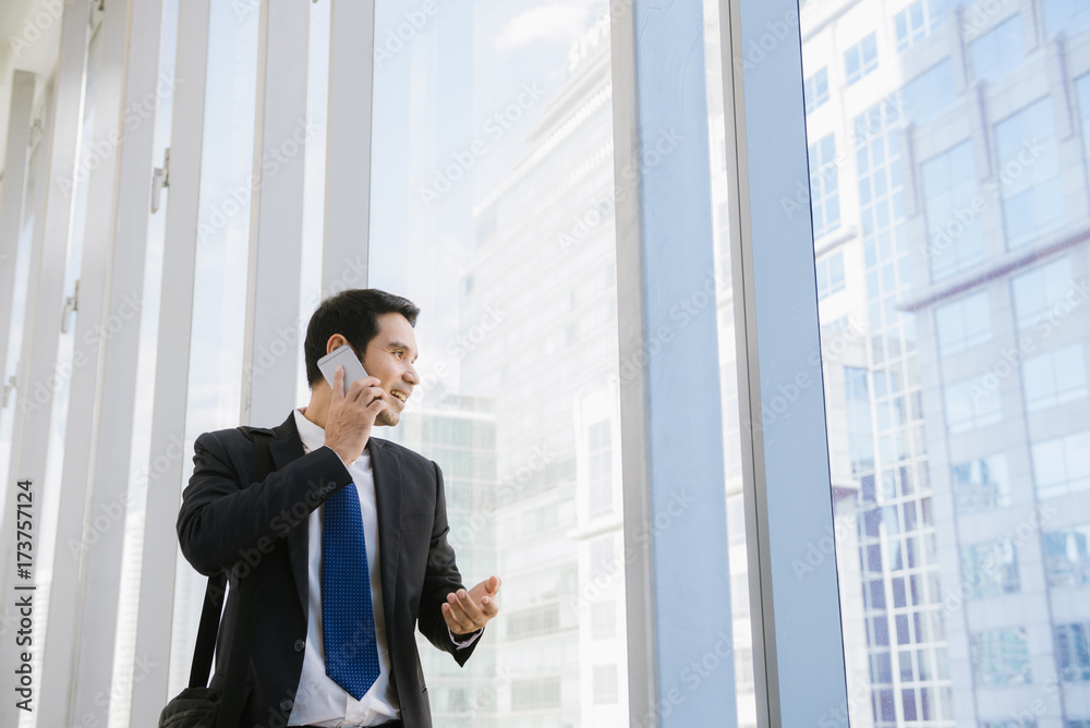 Man on smart phone - young businessman in airport. Casual urban professional business man using smartphone smiling happy inside office building. Handsome man wearing suit jacket indoors. Man on smart phone - young businessman in airport. Casual urban professional business man using smartphone smiling happy inside office building. Handsome man wearing suit jacket indoors.