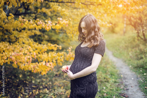 Portrait of pregnant woman belly in colorful autumn forest in September. Concept of pregnancy and the seasons