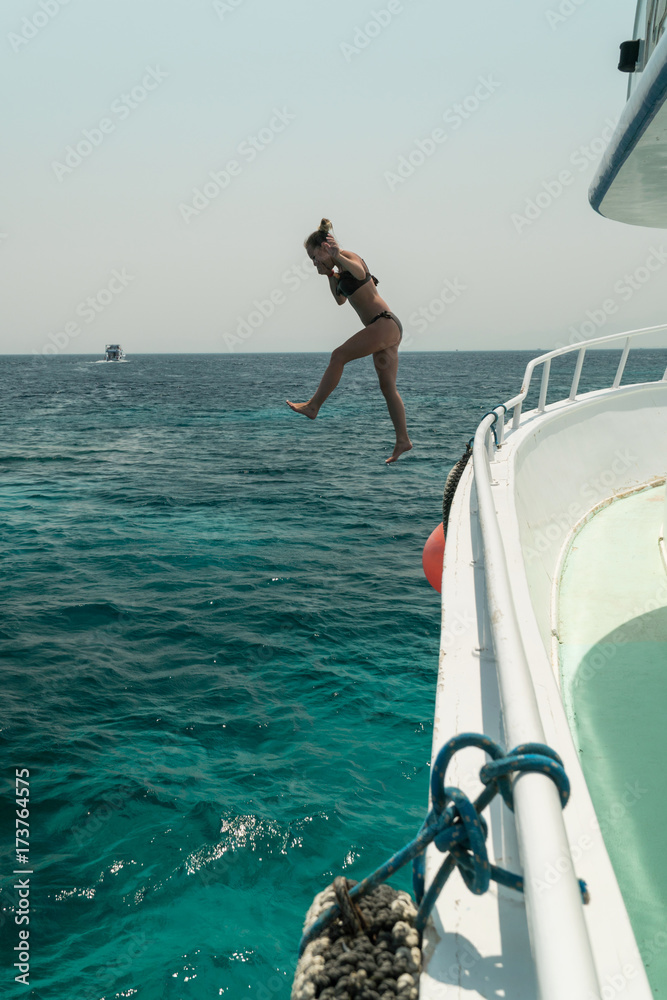 Naklejka premium Girl jump into the water from the yacht