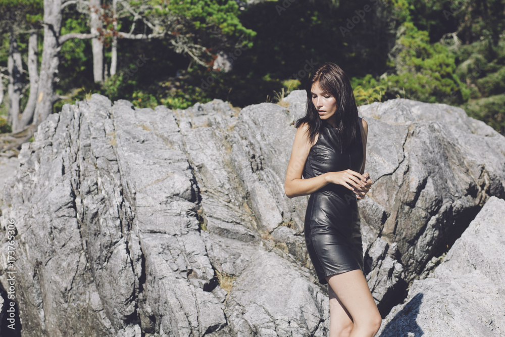 A beautiful girl in a leather dress by large rocks outside A beautiful girl in a leather dress by large rocks outside