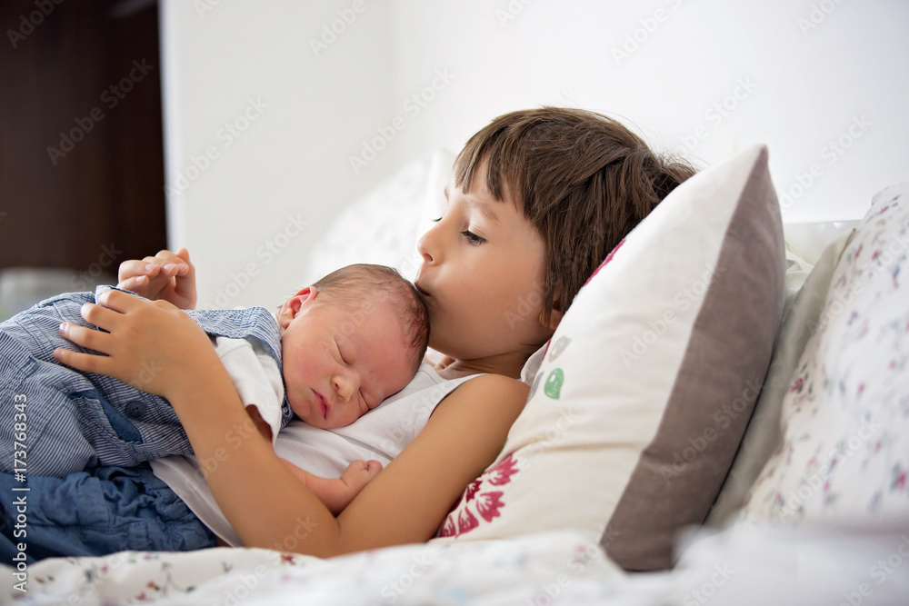 Beautiful boy, hugging with tenderness and care his newborn baby brother at home Beautiful boy, hugging with tenderness and care his newborn baby brother at home