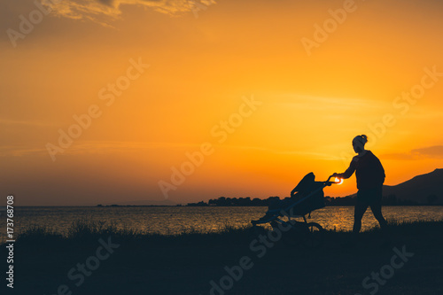 Mother walking on a beach with stroller enjoying motherhood