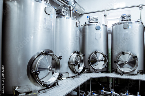 Rows of steel with large round hatches, modern production of beverages.