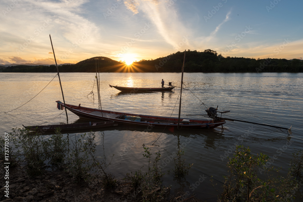 Fisher man on Long tail Boat at Ranong estuary, Thailand, sunset at river