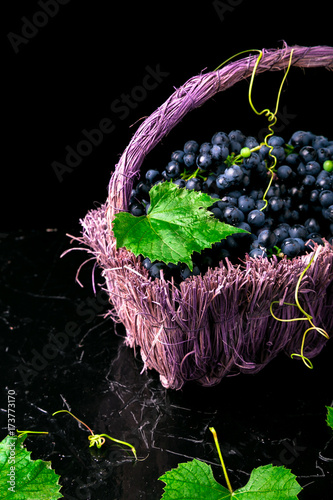 Red wine grapes in voiolet basket on bllack background. photo