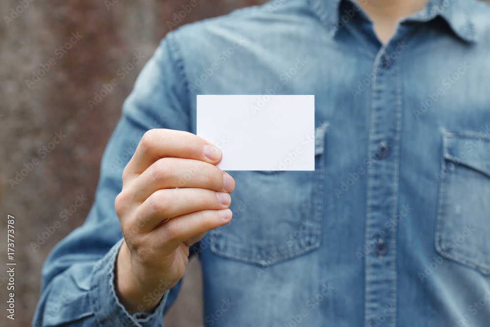 Man holding white business card on concrete wall background Man holding white business card on concrete wall background