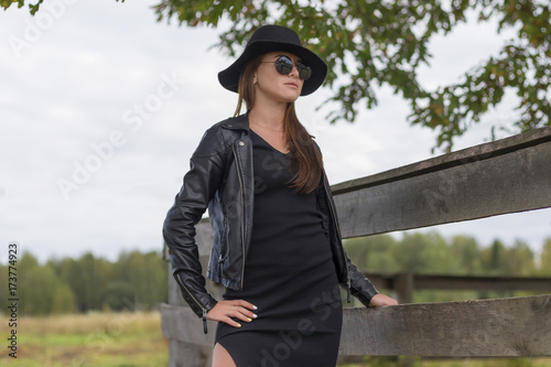 girl in a black dress, a hat and sunglasses outside the city photo