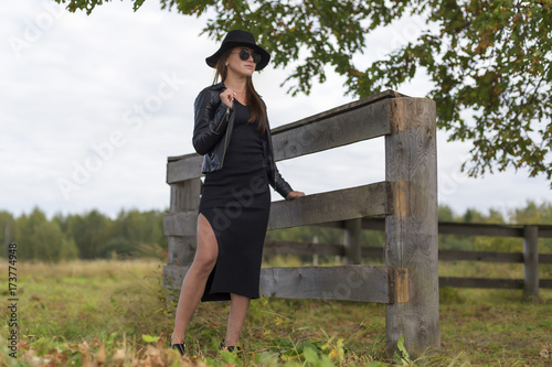 girl in a black dress, a hat and sunglasses outside the city photo