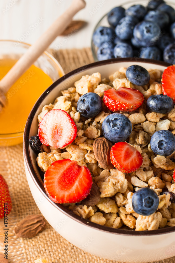 Fototapeta premium Healthy breakfast concept with oat flakes and fresh berries on rustic background. Food made of granola, muesli. Healthy banana smoothie with blackberries, muslie, strawberries, blueberries and honey.