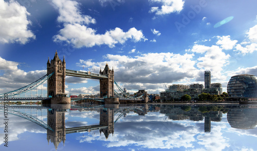 Tower Bridge spanning the River Thames with a dramatic blue cloudy sky and good water reflection