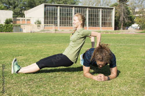 Beautiful young couple doing a workout together on a football field. Early morning workout. Living a healthy lifestyle.