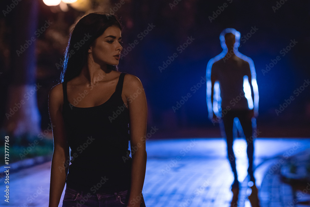 Φωτογραφία The woman stand on the dark street on the background of the man