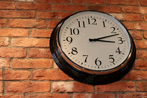 Large round clock on a brick wall
