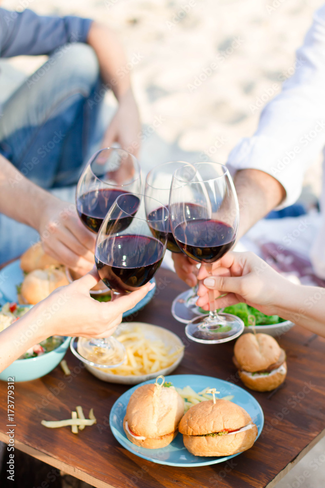      Hands Friends toasting red wine glass and having fun outdoors.