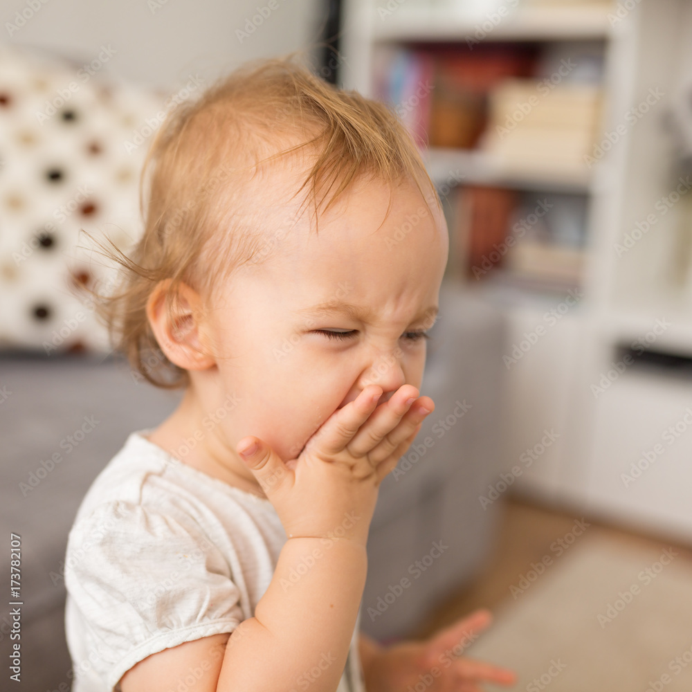 One year old girl yawning and putting her hand in front of her mouth One year old girl yawning and putting her hand in front of her mouth