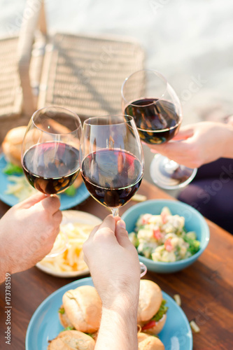      Hands Friends toasting red wine glass and having fun outdoors.