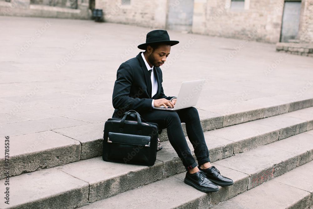 Businessman sitting on stairs working with his laptop. Businessman sitting on stairs working with his laptop.