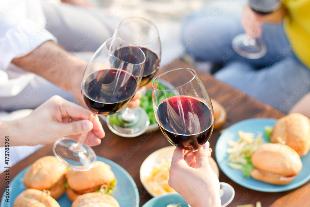 Hands Friends toasting red wine glass and having fun outdoors.