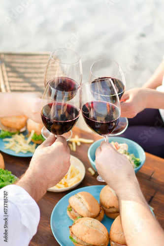  Hands Friends toasting red wine glass and having fun outdoors.