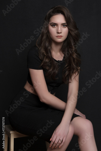 portrait of a beautiful girl in black clothes sitting dark background © Анна Антонова