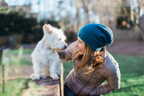 A beautiful woman talking a cute small white dog