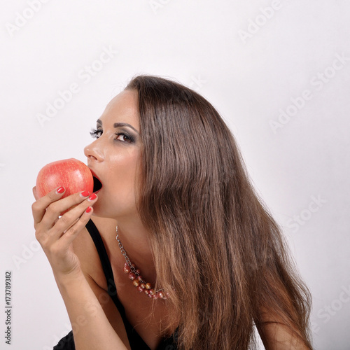 beautiful woman with dark hair eating an apple.