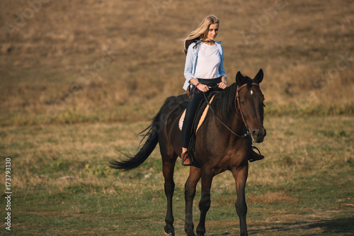 Beautiful young cowgirl riding her horse in field © antgor