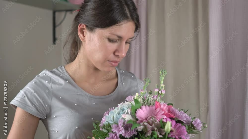 Female florist finishes making a bouquet of flowers in a hat box and happily looks at him close-up 4k. Female florist finishes making a bouquet of flowers in a hat box and happily looks at him close-up 4k.