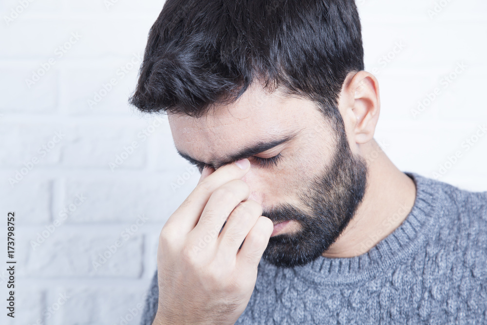 Fototapeta premium Mid adult man with headache pinching his nose at home