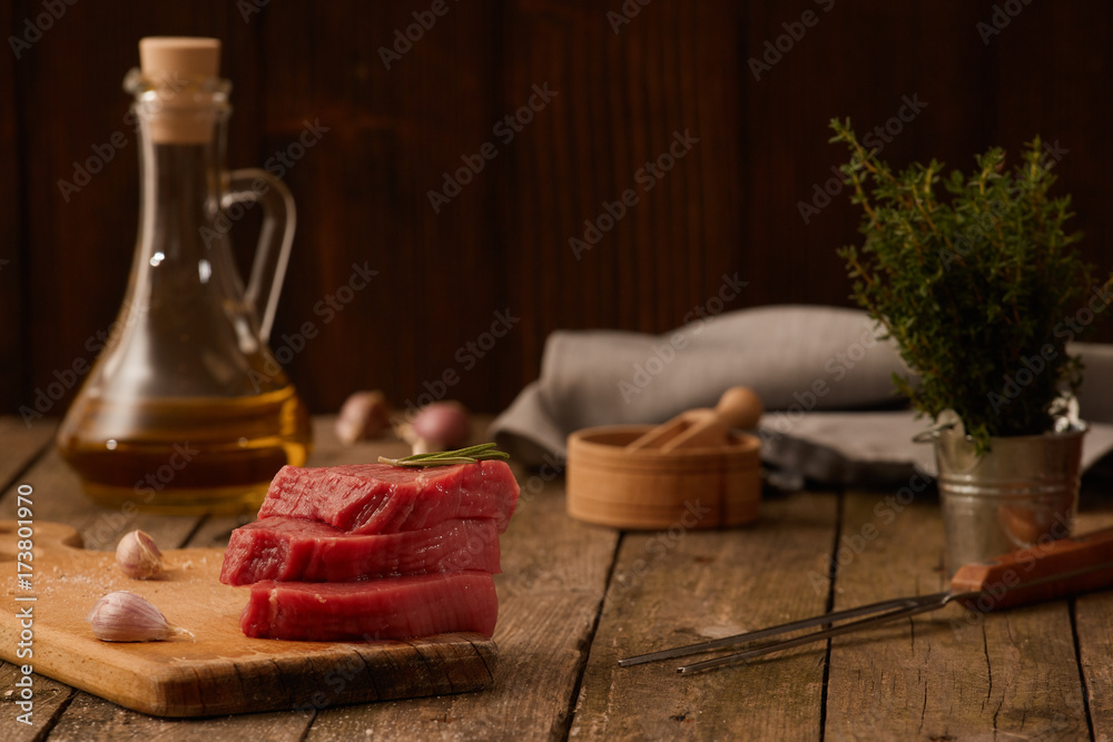 Raw beef meat steak on rustic background with herbs.  Copy space.