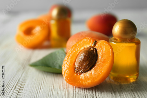 Bottle of apricot oil with fresh fruit on wooden table