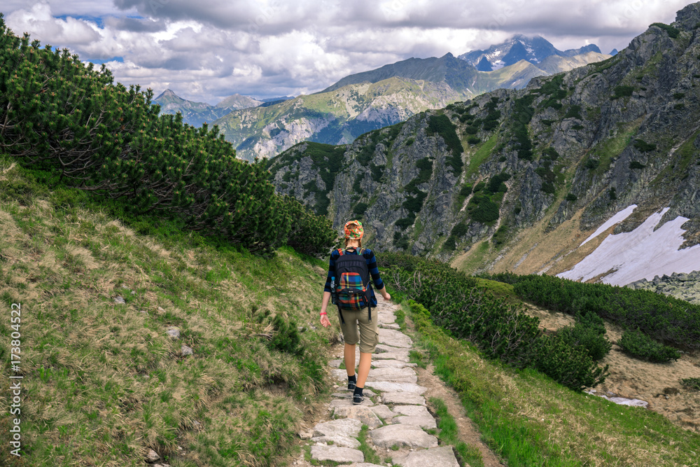 GIrl with backpack trekking on the rocky path in Tatra mountains, Poland