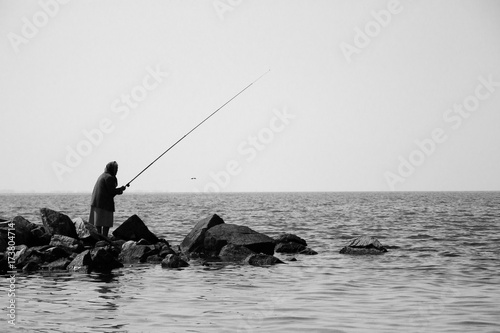Single old woman is fishing on a stones 