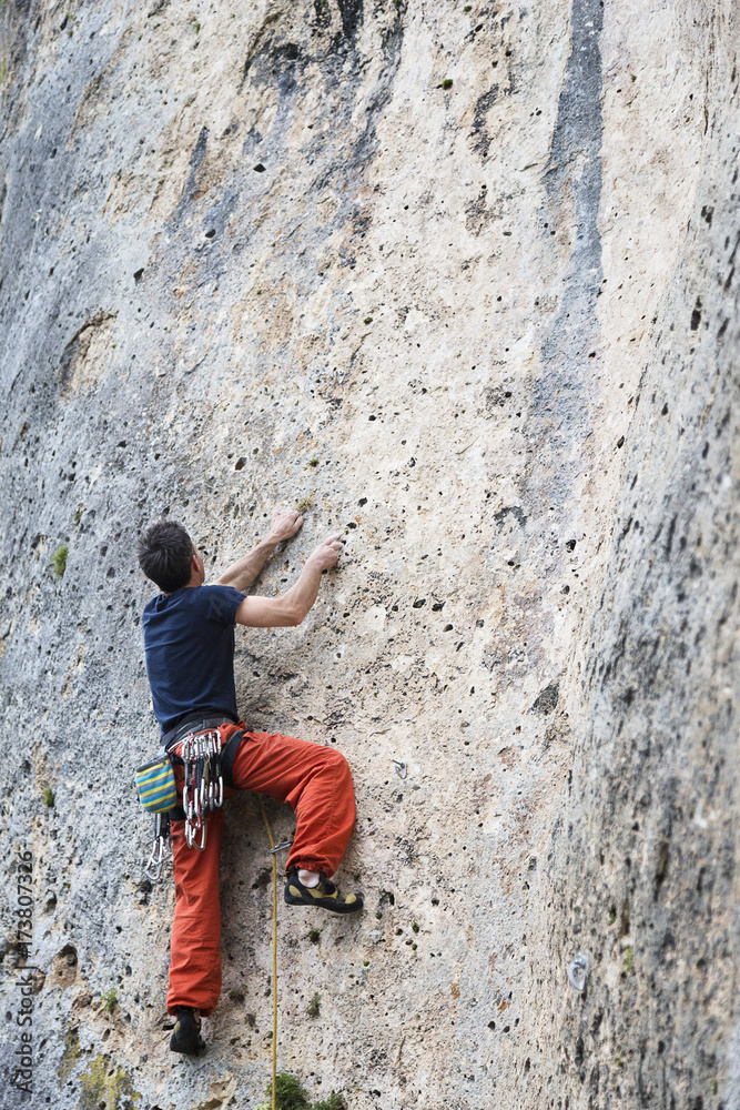 Rock climber climbing a vertical wall outdoors Rock climber climbing a vertical wall outdoors