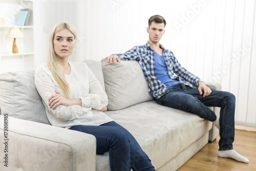 The unhappy woman sit near the man on the sofa