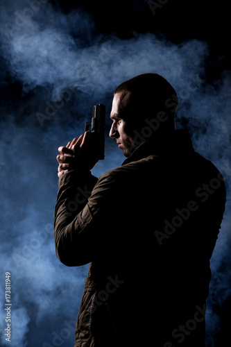 detective or criminal with gun on foggy night background
