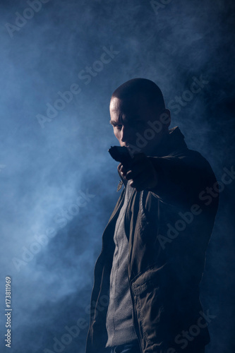 detective or criminal with gun on foggy night background