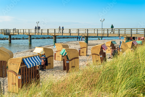 Fototapeta Naklejka Na Ścianę i Meble -  The northeastern seaside resort Wustrow at the baltic sea in Germany. The popular village on the Darss, Fish Land, with the white sandy beach and the picturesque  roofed wicker beach chairs