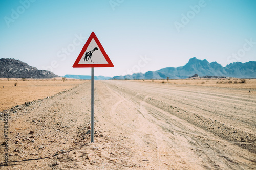 empty desert road with a yield for Giraffes sign post photo
