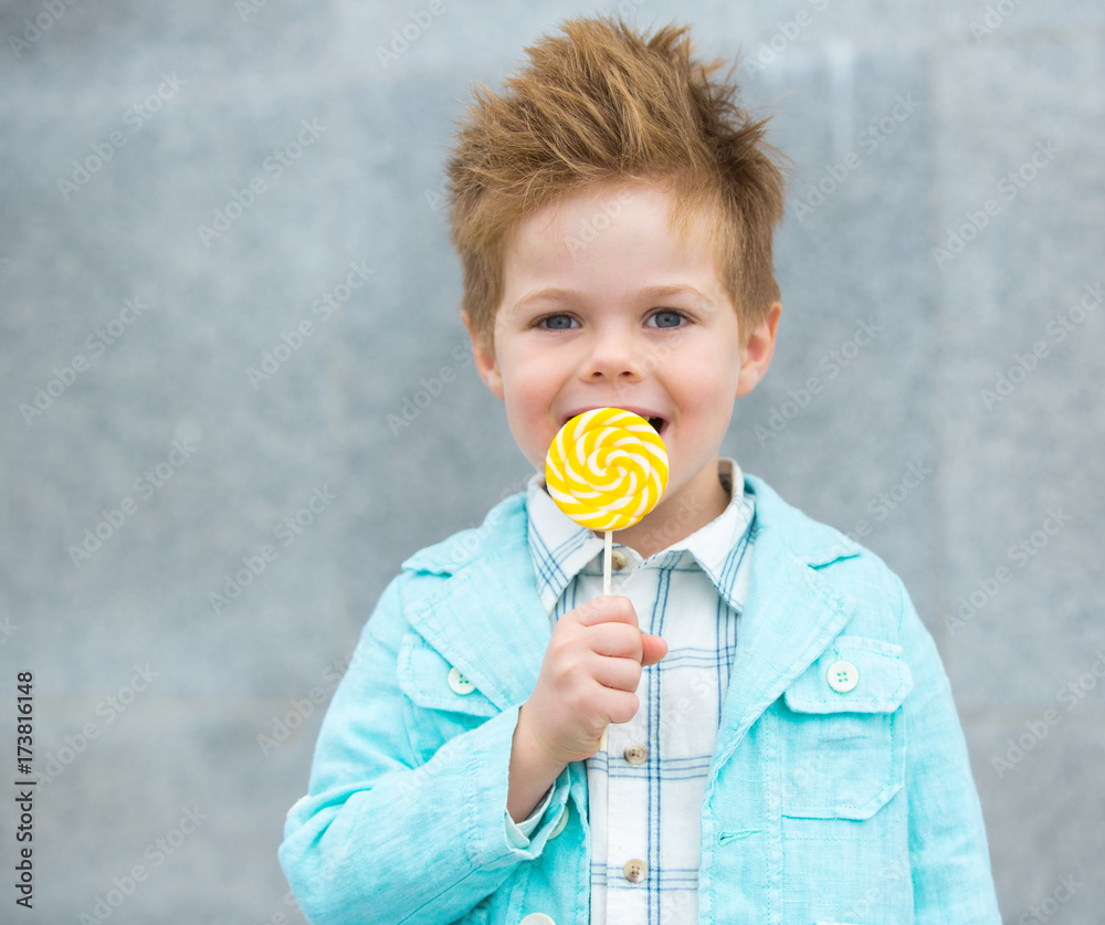 Fashion kid with lollipop near gray wall Fashion kid with lollipop near gray wall
