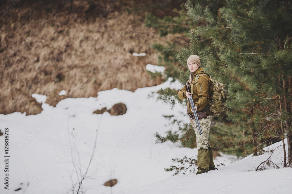 Female hunter in camouflage clothes ready to hunt, holding gun and walking in forest. Female hunter in camouflage clothes ready to hunt, holding gun and walking in forest.