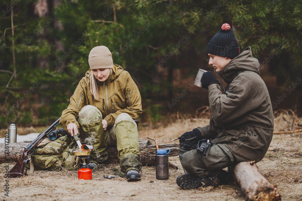 .Two hunters are eating together in the forest. Bushcraft, hunting and people concept .Two hunters are eating together in the forest. Bushcraft, hunting and people concept
